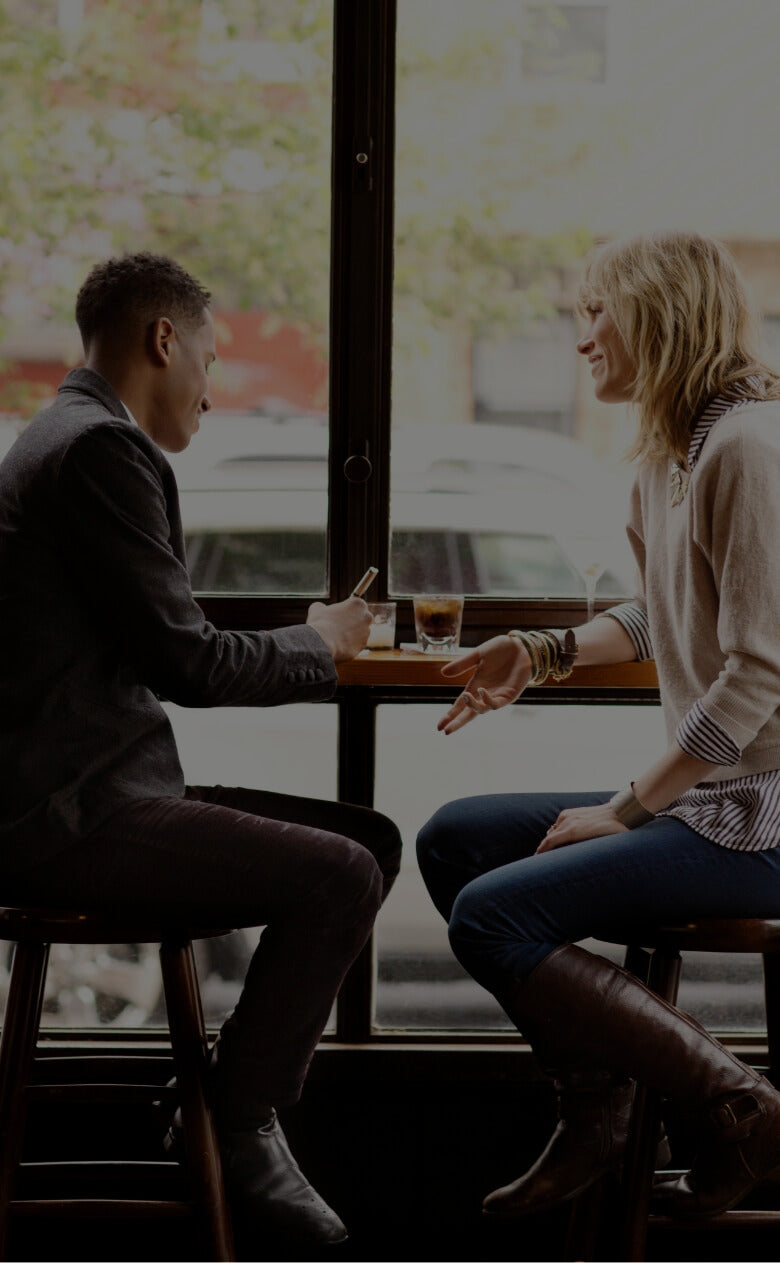 Two business professionals discussing opportunities at a cafe counter.